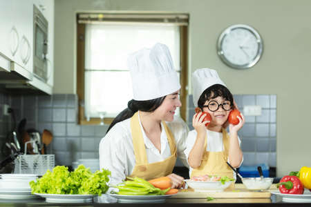 Cooking Family. Chef kid boy and mother making and leaning fresh vegetables salad for healthy eat and education.  Asian son helping make food, so happy and enjoy.  Family Lifestyle Conceptの写真素材