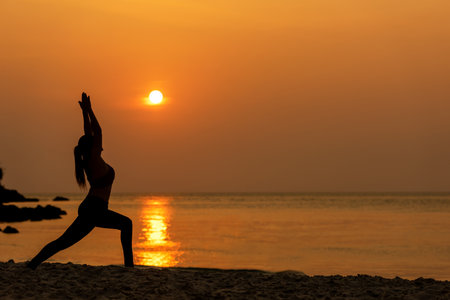 Lifestyle woman yoga exercise and pose for healthy life. Young girl or people pose balance body vital zen and meditation for workout silhouette sunset beach and sea background. Healthy Conceptの写真素材