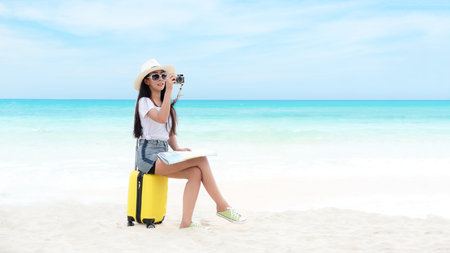 Happy traveler and tourism young women travel summer on the beach. Asian smiling people holding smartphone take photo  and sitting on yellow suitcase for relax outdoor destination leisure trip travel in holidayの写真素材