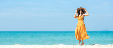 Summer vacations. Lifestyle woman relax and chill on beach background.  Asia happy young people wearing yellow dress fashion summer trips walking enjoy  tropical beachの写真素材