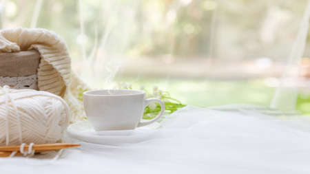 Coffee morning.  White steaming cup of hot coffee for relax after working hobbies crochet on white wooden near windowの写真素材