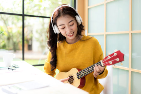 Young woman happy listen music for chill and relax after finish work.   Lifestyle girl using laptop for meeting and working  in living room at home.  Lifestyle Conceptの写真素材