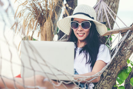 Lifestyle freelance woman using laptop working and relax on the beach.Â  Asian people success and together your work pastime and meeting conference on internet in holiday. Business and Summer Conceptの写真素材