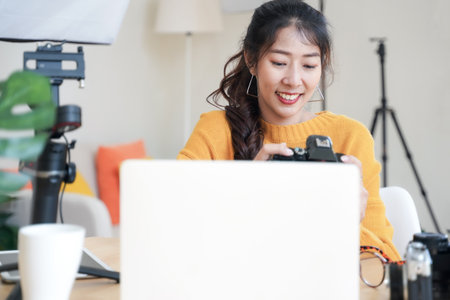Lifestyle Asia young women photographer and freelance holding a dslr camera in  home office.  Female photographer smiling cheerfully working new project in studioの写真素材