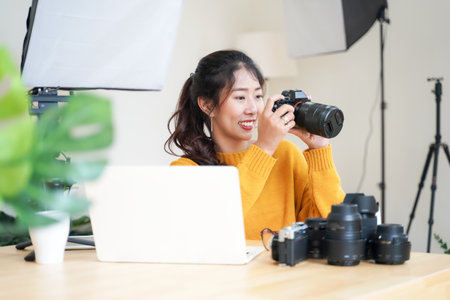 Lifestyle Asia young women photographer and freelance holding a dslr camera in  home office.  Female...