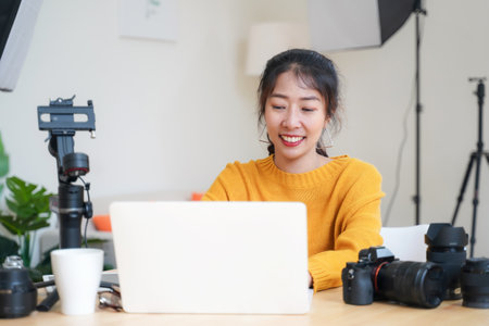 Lifestyle Asia young women photographer and freelance holding a dslr camera in  home office.  Female photographer smiling cheerfully working new project in studioの写真素材