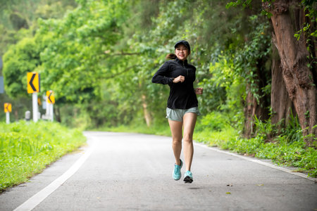 Healthy woman jogging run and workout on road outdoor. Asian runner people exercise gym with fitness session, nature park background. Health and Lifestyle Conceptの写真素材