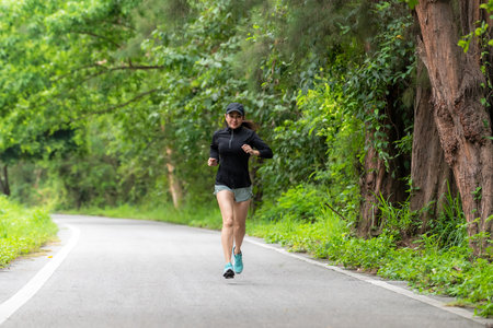 Healthy woman jogging run and workout on road outdoor. Asian runner people exercise gym with fitness session, nature park background. Health and Lifestyle Conceptの写真素材