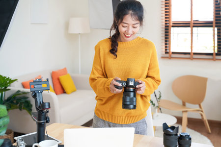 Lifestyle Asia young women photographer and freelance holding a dslr camera in  home office.  Female photographer smiling cheerfully working new project in studioの写真素材