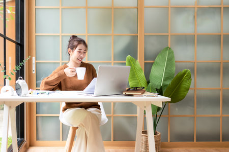 Young people work from home checking report for presentation with laptop morning relax at home. Asia woman meeting conference connect online with office.  Business and Technology Conceptの写真素材