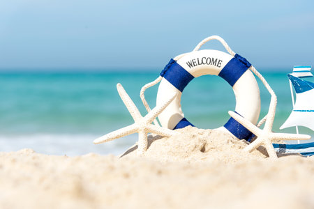 Lifebuoy on sand beach background with starfish and fishing boat, copy space. Summer Travel Conceptの写真素材
