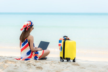 Lifestyle freelance woman using laptop working on the beach.Â  Asian people success and together your work pastime and meeting conference on internet in holiday. Business and Summer Conceptの写真素材
