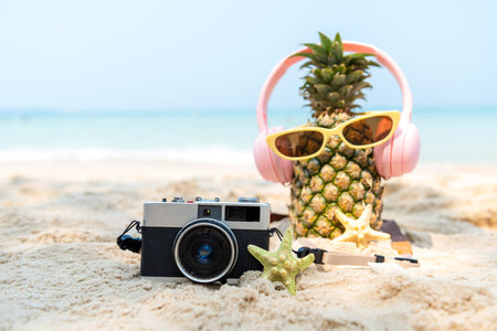 Select focus. Summer in the party.  Hipster Pineapple Fashion in sunglass and listen music with vintage camera on the sand beach beautiful blue sky background.  Fashion Summer Vacation Conceptの写真素材