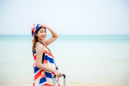Summer vacations. Lifestyle  woman relax and chill on beach background.  Asia happy young people walking with bag travel suitcase luggage fashion dress.  Summer trips travelの写真素材