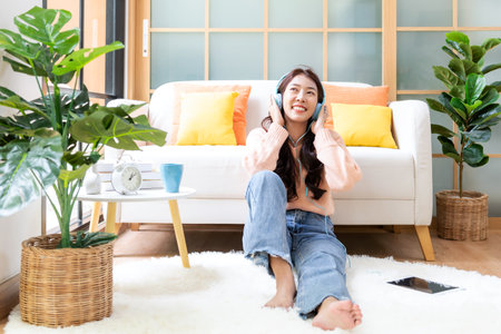 Home lifestyle woman relaxing lying down in living room. Happy girl shopping and listen music on laptop for wellness and health in weekend holiday.  Lifestyle Conceptの写真素材