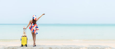 Summer vacations. Lifestyle  woman relax and chill on beach background.  Asia happy young people with bag travel suitcase luggage fashion dress raise arm wave sea, summer trips travel copy space bannerの写真素材