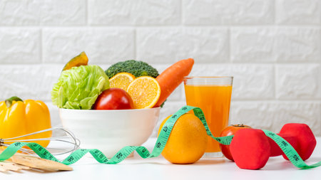 Select focus. Diet and healthy fresh vegetable fruits for detox body slim fit for health lifestyle with Sport exercise equipment workout and orange juice,  white background. Weight Loss and Diet Conceptの写真素材