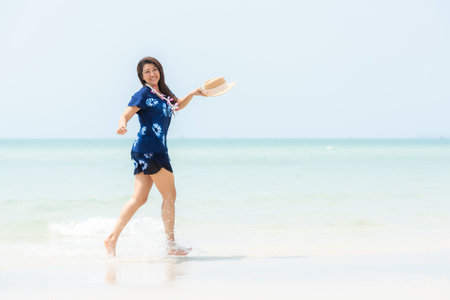 Summer vacations. Lifestyle woman relax and chill on beach background.  Asia happy young people jumping on the wave sea, summer trips walking enjoy tropical beach. Lifestyle and Travel Conceptの写真素材