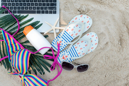 Summer Travel.  Top view laptop of tourism freelance working and vacation summer on the beach with sunblock and sandals.  Summer trip holidayの写真素材