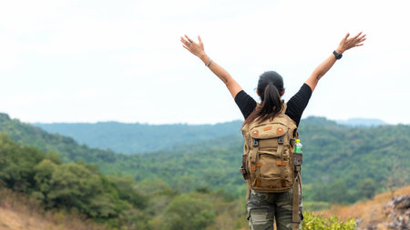 Hiker asian woman backpack raise hands happy feeling freedom good and strong weight victorious facing on the natural mountain. Traveler going camping outdoors destination leisureの写真素材