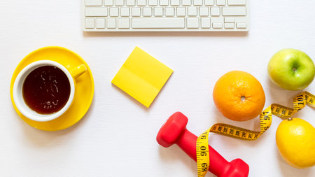 Healthy snack with working in the office.  Fresh fruit apple and cup black coffee, tape measure for diet Health care with keyboard on white wood background.  Healthy Lifestyle Concept, top viewの写真素材