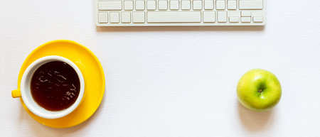 Healthy snack with working in the office.  Green apple yellow cup black coffee for diet Health life with keyboard on white wood background.  Healthy Lifestyle Concept, top view, copy space for bannerの写真素材