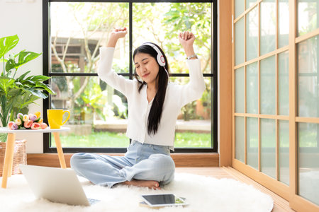 Young smiling woman happy listen music for chill and relax in summer holiday. Lifestyle girl using laptop for entertainment in living room at home.  Nature garden background.  Lifestyle Conceptの写真素材