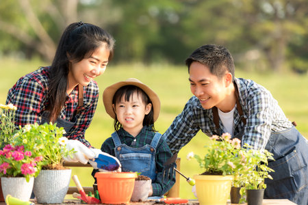 Family child girl helping parent care plant flower in garden. Young people mother, father and daughter gardening outdoor sunnyÂ  nature background. Happy and enjoy in spring and summer day.Â  Family Conceptの写真素材