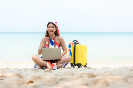 Lifestyle freelance woman using laptop working on the beach.Â  Asian people success and together your work pastime and meeting conference on internet in holiday. Business and Summer Conceptの写真素材