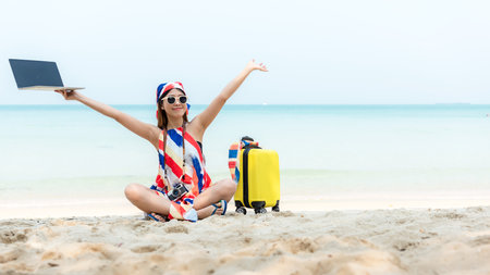 Lifestyle freelance woman raise arms relax after using laptop working on the beach. Asian people success and together your work pastime and meeting conference on internet in holidayの写真素材