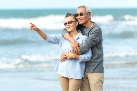 Asian Lifestyle senior couple walking chill and pointing on the beach happy in love romantic and relax time after retirement.Â  People tourism elderly family travel leisure and activity after retirement in vacations and summerの写真素材