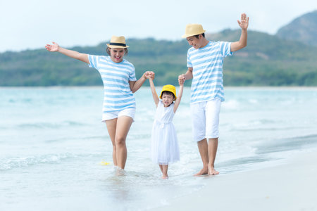 Asian happy family have fun water sea on the beach.  Parent and daughter traveling backpack for travel in vacations for leisure and destination.  Family tourism travel in summer and holiday.  Travel and Family Conceptの写真素材