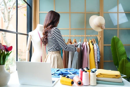 Young women fashion designer using laptop working and design tailor and cloth in the showroom,  Lifestyle Stylish tailor taking measurements on mannequin for cutting cloths in studio.  Business and Industry small Conceptの写真素材