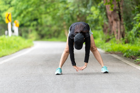 Healthy woman warming down stretching her legs and looking away in the road outdoor. Asian runner woman workout before fitness and jogging session at the park. Health care Lifestyle Conceptの写真素材