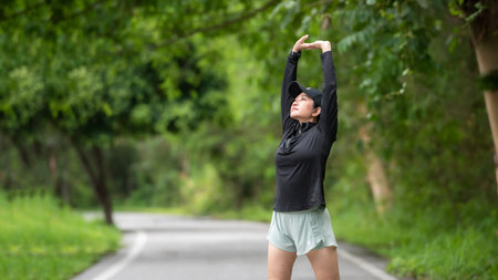 Healthy woman warming up stretching her arms. Asian runner woman workout before fitness and jogging session on the road nature park. Healthy and Lifestyle Conceptの写真素材