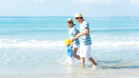 Asian happy family have fun water sea on the beach.  Parent and daughter traveling backpack for travel in vacations for leisure and destination.  Family tourism travel in summer and holiday.  Travel and Family Conceptの写真素材