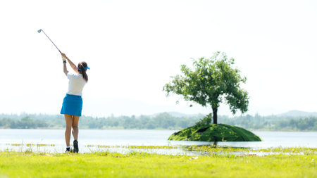 Healthy Sport. Asia golf woman golfer player chips and swing golf on the green Floating water.  people golf presumably does exercise and hobby in holiday. Healthy Lifestyle Concept.の写真素材