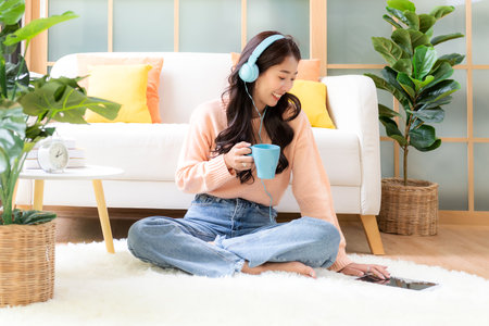 Happy young woman drinking hot coffee after working and meeting online at home. Lifestyle freelance relax and chill in living room. Lifestyleの写真素材