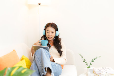 Happy young woman drinking hot orange cup coffee after working and meeting online at home.  Lifestyle freelance relax and chill  in living room.  Lifestyle Conceptの写真素材