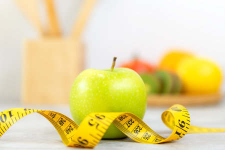 Close up fresh apple and tape measure.  Healthy snack for diet planning.  Kitchen item background.  Healthy Lifestyle Conceptの写真素材