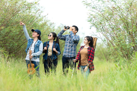 Group asian friends traveler with backpack adventure holding map to find directions and walking relax in the jungle forest outdoor for destination leisure explore educationの写真素材