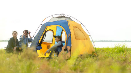 Camping outdoor. Group  friends camping leisure and destination travel. Family sitting around camp fire and playing guitar and roasted sausages, tourism relax and travel near riverの写真素材