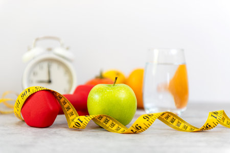 Close up green apple and dumbbell.  Healthy snack for diet planning.  Fresh  fruit with green fruit and tape measure white background.  Healthy Lifestyle Conceptの写真素材