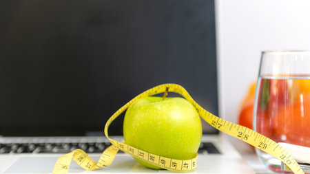 Close up green apple and tape measure.  Healthy snack for diet planning for working in office.  Fresh fruit dumbbell and laptop background.  Healthy Lifestyle Conceptの写真素材