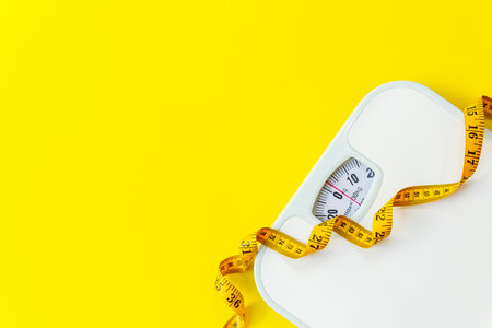 Weight loss control planning.  White scale and measuring tape for body dieting healthy life.  Yellow background. Top view copy space for textの写真素材