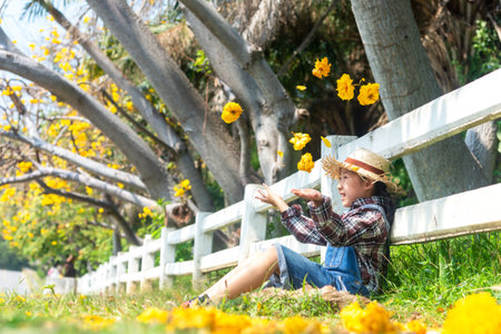 Asian kid girl sitting chill outdoor in fallen leaves autumn in meadow the park, happy and relax in summertime and vacation day. Lifestyle Conceptの写真素材