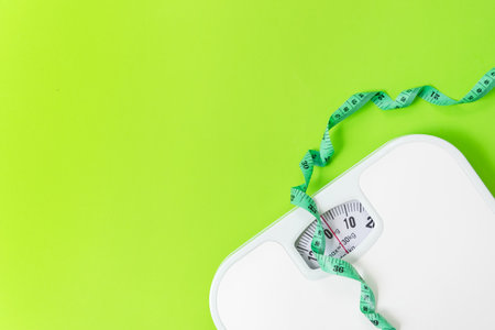 Weight loss control planning.  White scale and measuring tape for body dieting healthy life.  Green background. Top view copy space for bannerの写真素材