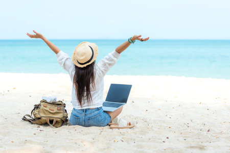 Lifestyle freelance woman raise arms relax after using laptop working on the beach.Â  Asian people success and together your work pastime and meeting conference internet in holidayの写真素材