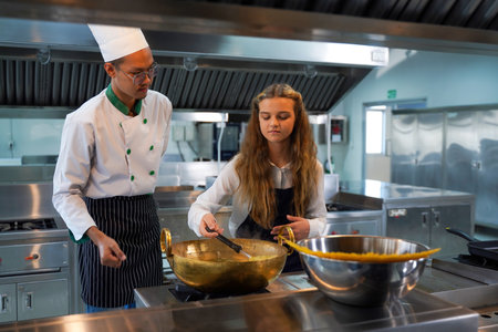 Children girl leaning cooking food.  Chef teacher teaches cooking to the group children in class kitchen room.  Chef preparing student for learning marking food at workshopの写真素材