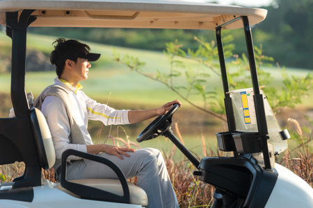 Golfer asian man sitting on the car golf go to golf course shot continue game.  Hobby in holiday and vacations in sunny morning day on club golf. Lifestyle and Sport Conceptの写真素材